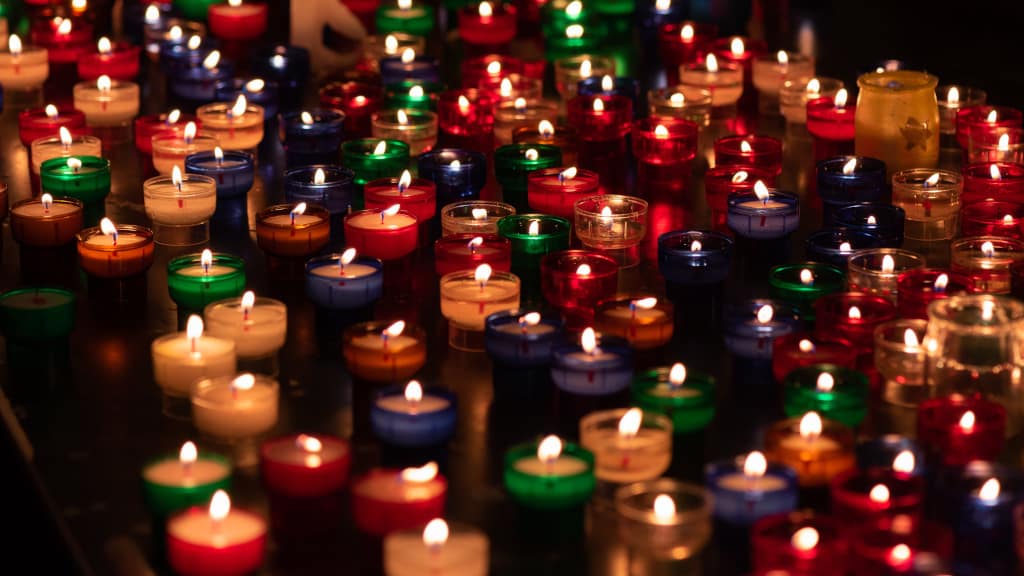Symbolbild Menge an brennenden Kerzen; Bild: unsplash.com/Eduardo Casajús Gorostiaga